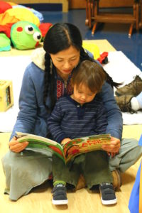 A mom with child on her lap, reading a book