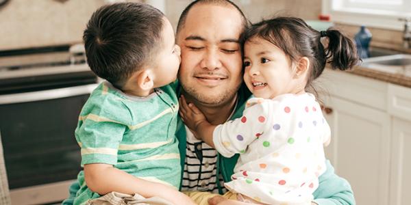 father with two children hugging and kissing