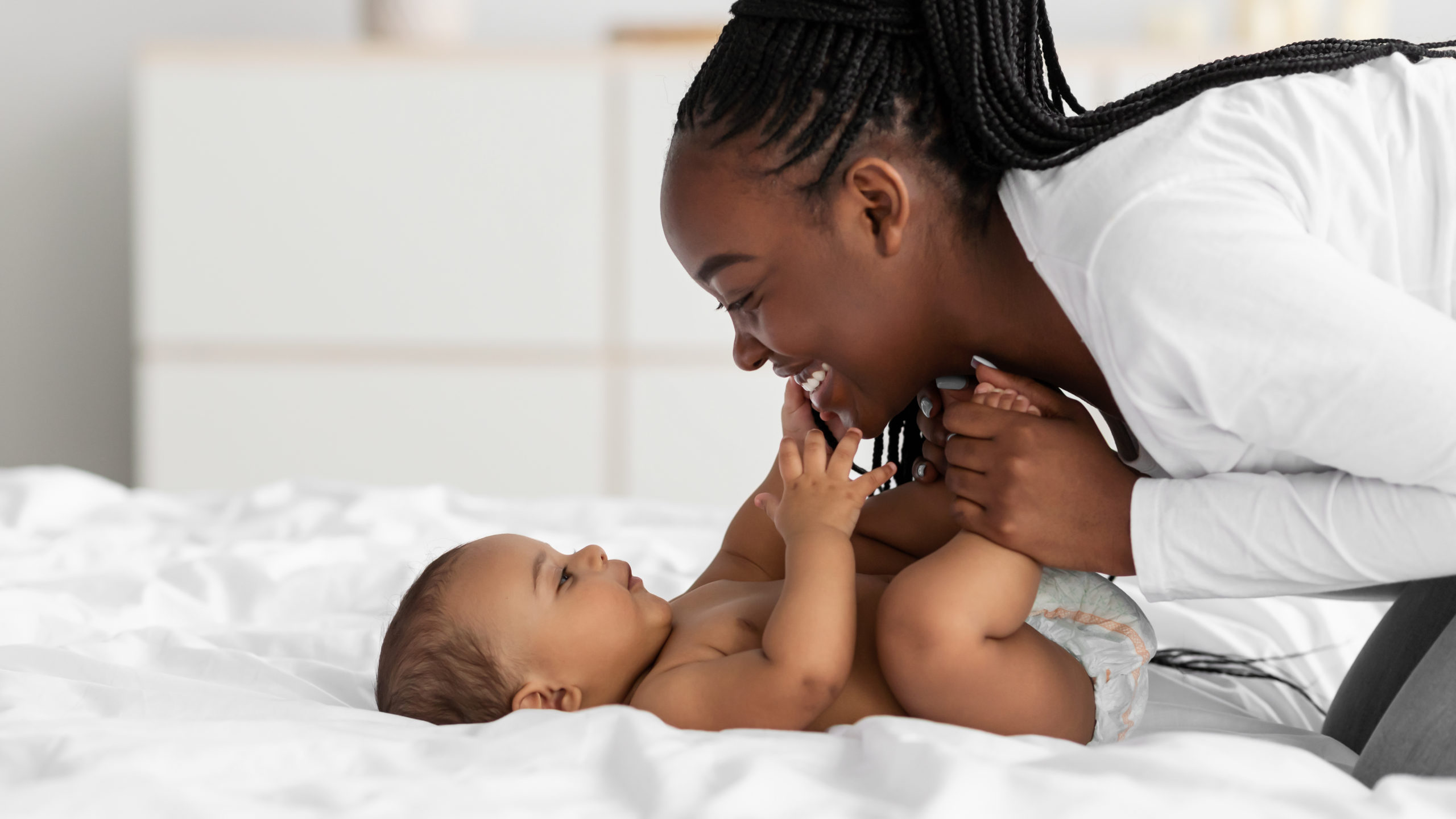 mom playing in bed with her baby