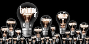 Photo of light bulbs with shining fibers in a shape of TRAINING, SKILLS and KNOWLEDGE concept related words isolated on black background