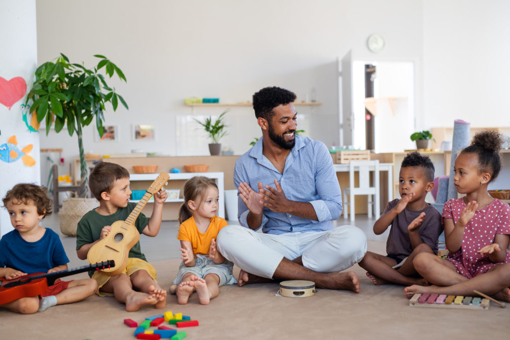 Preschool teacher with musical instruments & group of young children