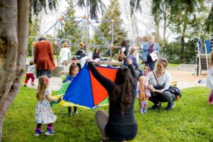 young children and caregivers around a parachute